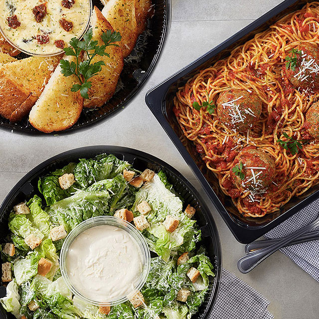 A flatlay of Italian food: spaghetti and meatballs, salad, and toasted bread with a dip.
