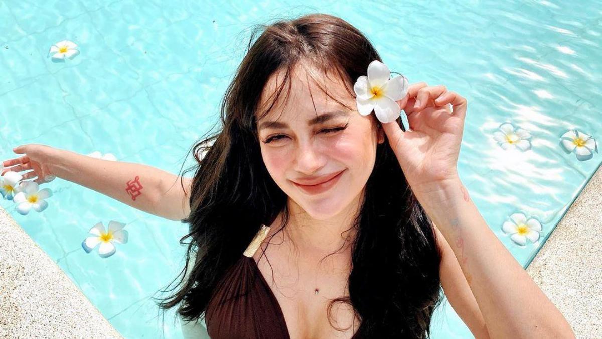 A picture of Arci Munoz smiling and winking at the camera while in a pool.