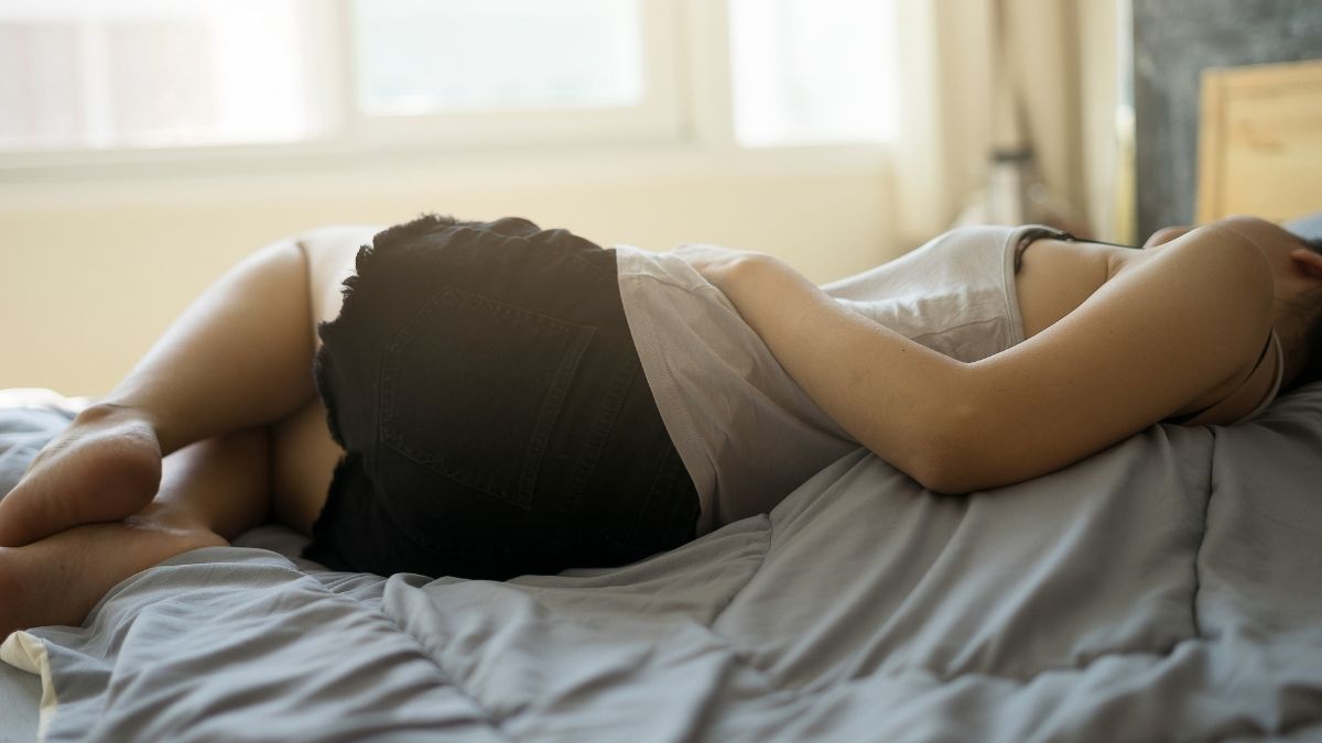 a stock image of a woman with her hand on her stomach, turned away, experiencing menstruation pain