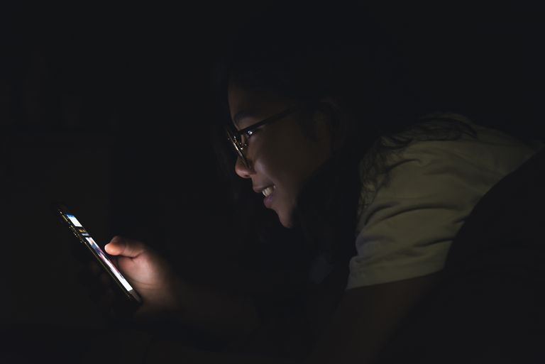 How to get back to sleep if you wake up in the middle of the night: girl using cellphone at night 