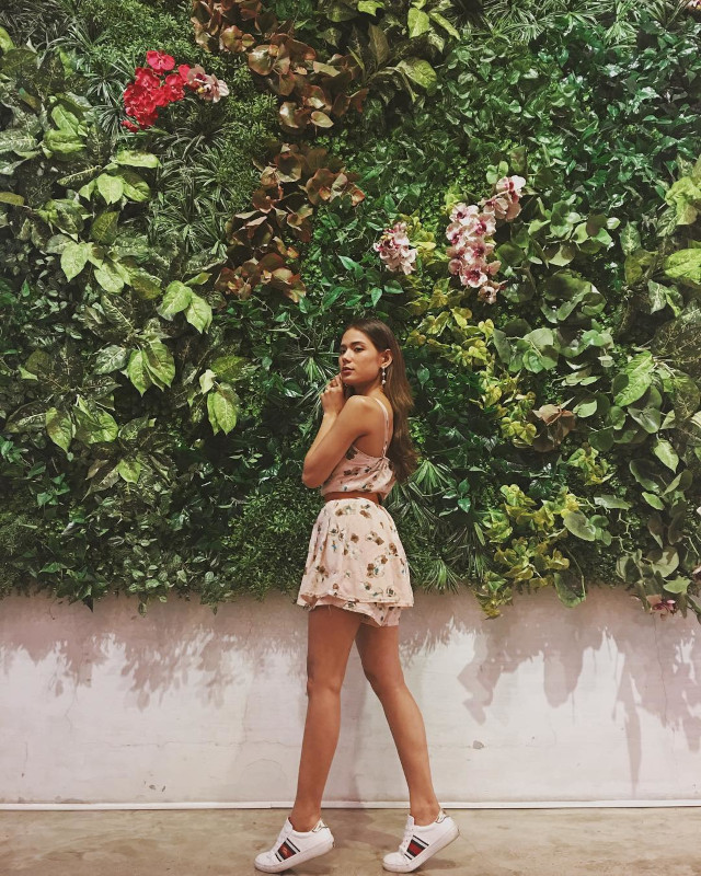 Devon Seron posing against a floral wall