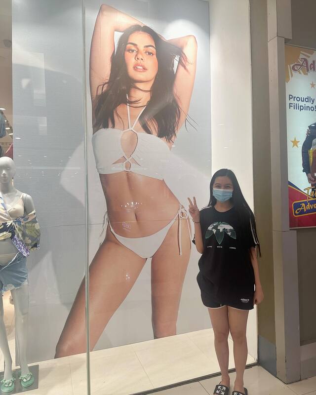 Jennica Garcia posing in front of Janine Gutierrez's ad