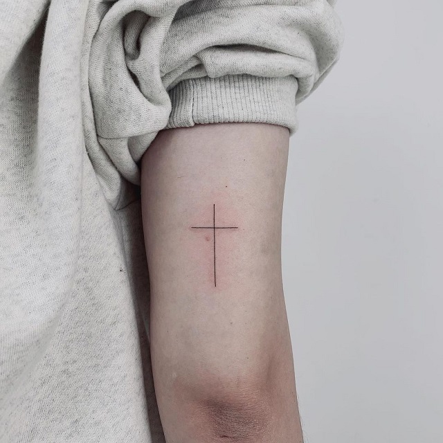 Fine line cross with flowers tattoo on the wrist