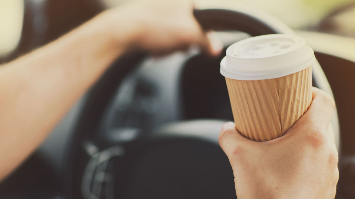 A driver having coffee behind the wheel