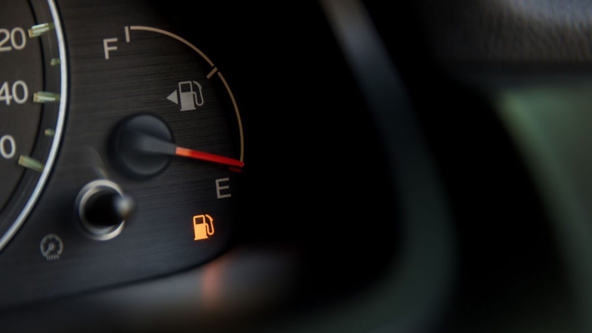 The low fuel warning light illuminated in the fuel gauge of a car