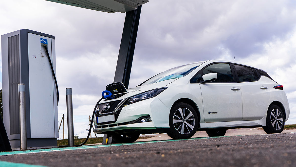 photo of a white Nissan Leaf at a charging station