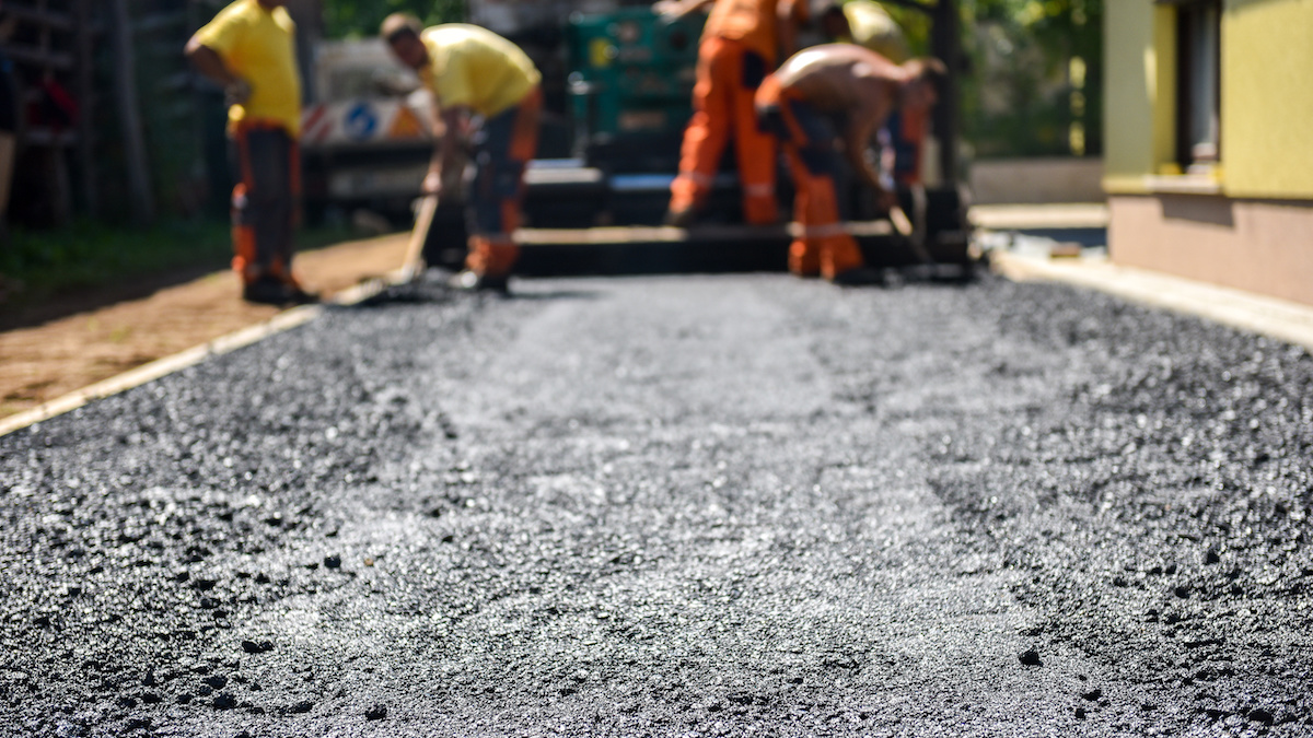 Workers laying down asphalt on a road