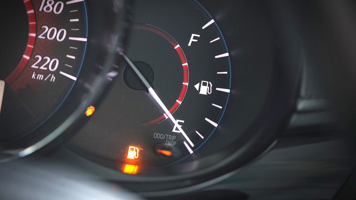 Image of a car’s fuel gauge with the needle almost pointing at empty and the low fuel light on