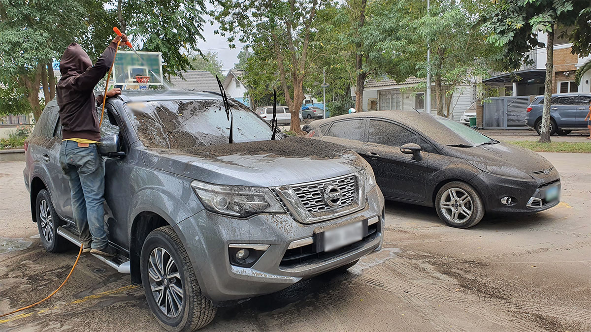 Man cleaning cars covered in volcanic ash