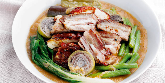 lechon kawali kare kare with fried pork belly chunks and vegetables in peanut sauce in a white bowl