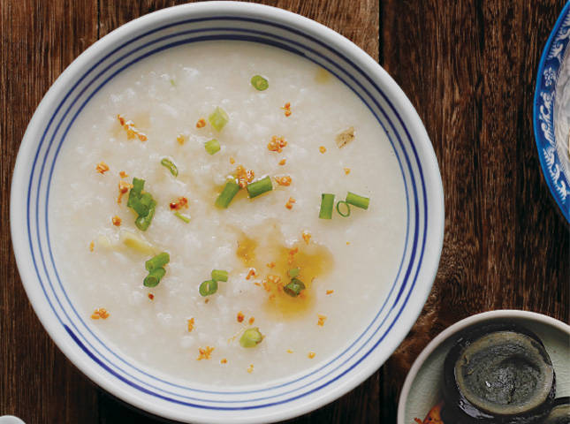 congee topped with sesame oil in a white porcelain bowl