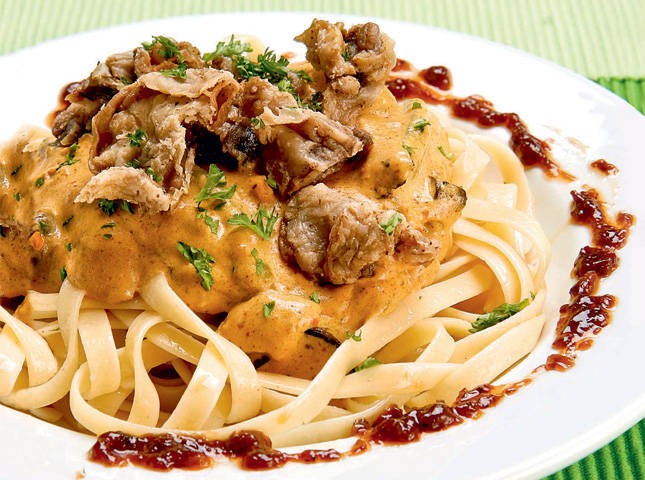 pasta cooked in kare-kare sauce with bagoong on the plate