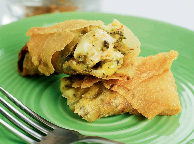 chicken, pesto, and cheese filled lumpia cut in half to reveal fillings