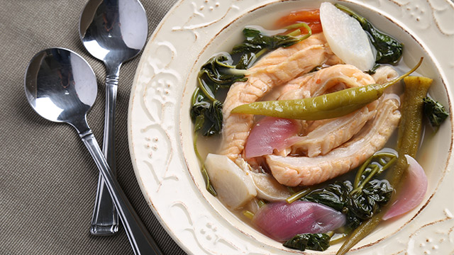 salmon belly sinigang in a shallow white bowl