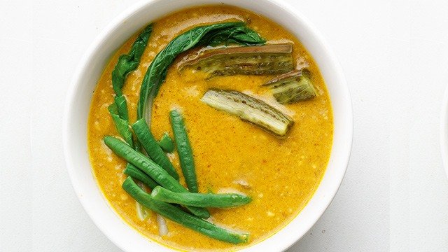 kare-kare sauce with sitaw, bok choy and eggplant in a white bowl
