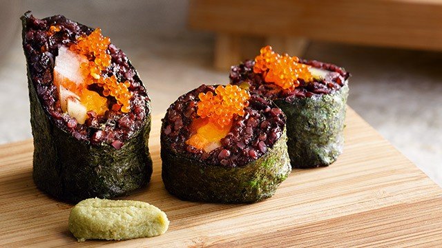 purple rice sushi filled with kani or imitation crab and topped with fish roe