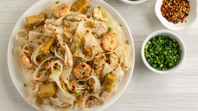 chicken and shrimp pad thai with chopped chives and chili flakes on the side 