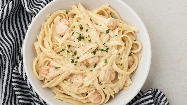 Creamy garlic butter shrimp pasta dish topped with parmesan.