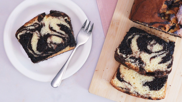 marble loaf cake sliced with cake slice on a plate and fork