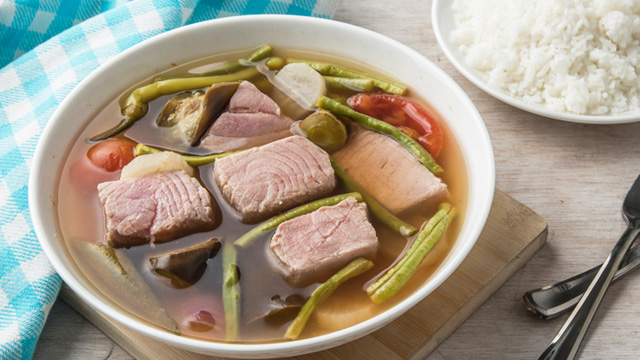 sinigang na tuna in a big white serving bowl and rice on a plate off to the side