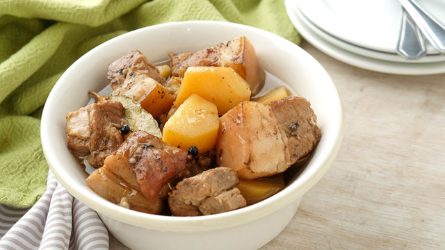 Pork adobo with potatoes in a white bowl