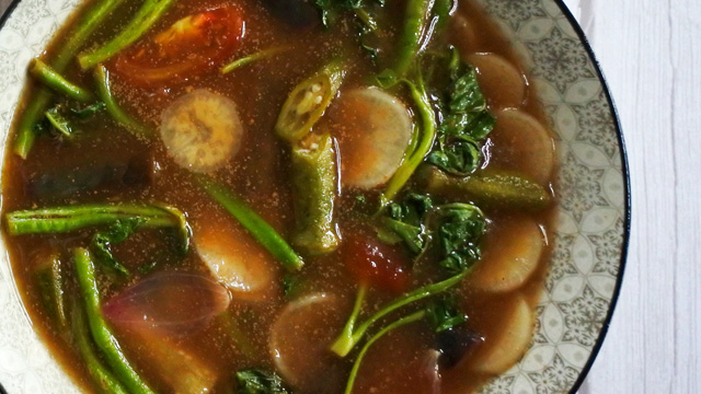 vegetable sinigang with radish, sitaw, kangkong, tomatoes, and okra in a patterned ceramic bowl