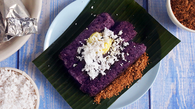 puto bumbong topped with butter and coconut on a banana leaf