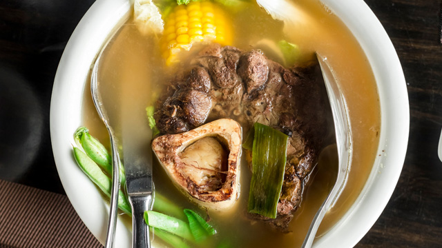 bowl of bulalo with stainless ladles in it
