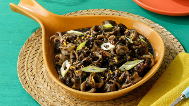adobong pusit in an orange serving plate, topped with green onion slices