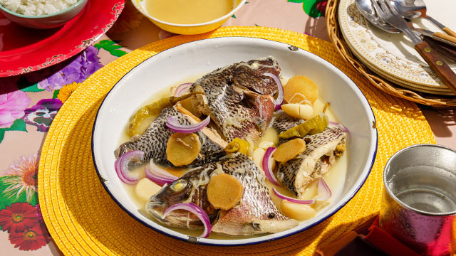 paksiw na tilapia on a white plate and a bright yellow abaca placemat