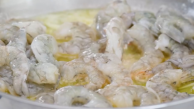 uncooked peeled and deveined shrimp added to a pan with garlic butter oil