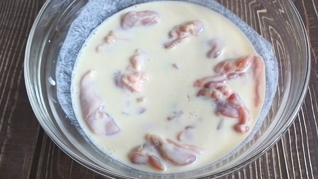 buttermilk mixture with raw chicken pieces marinating in a bowl