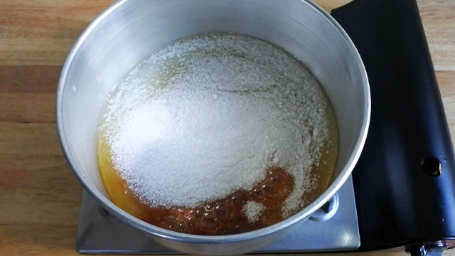 melting sugar in cake pan over flame from a portable butane stove 