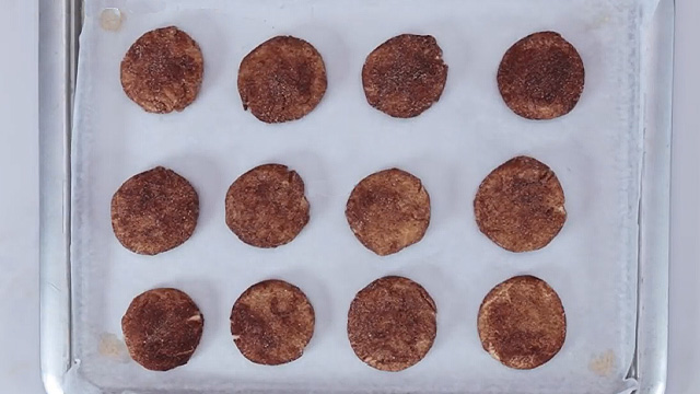 flattened cookie dough balls on a baking sheet