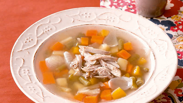 chicken slivers in a clear soup with carrots and corn