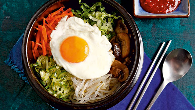 bibimbap topped with zucchini, carrots, mushrooms, and a fried egg